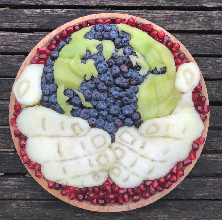 Hands holding the planet made out of fruit