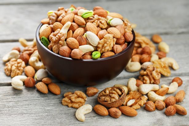 Wooden bowl with mixed nuts on a wooden gray background. Healthy food and snacks, organic vegetarian meals. Walnut, pistachios, almonds, hazelnuts and cashews, walnut.